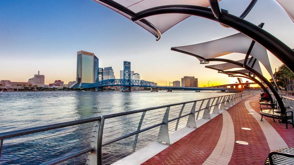 Walkway next to the river with city skyline in the background.